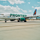 A Frontier Airlines plane taxis out from a terminal.